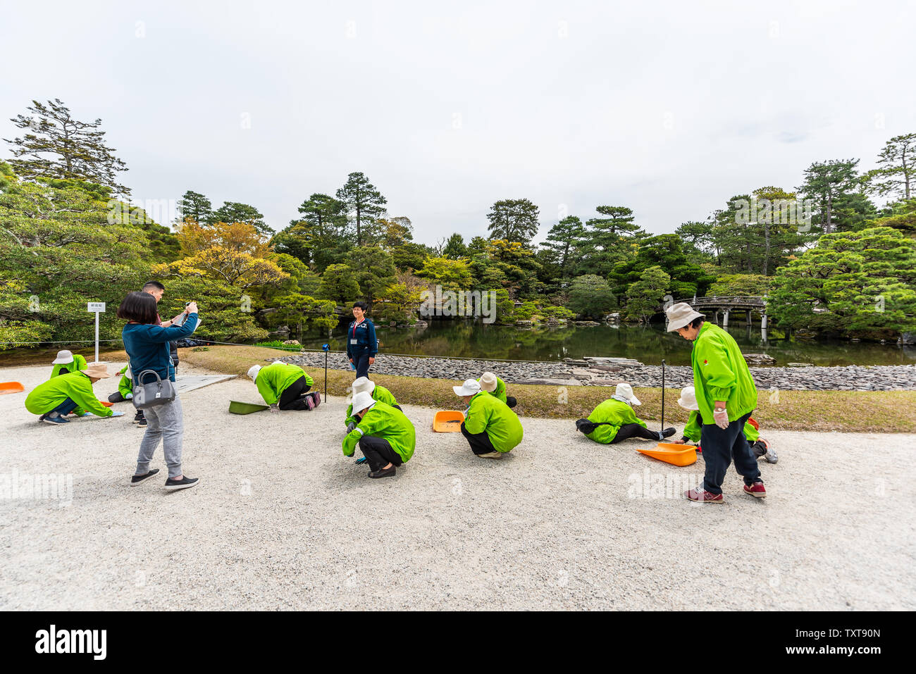 Kyoto, Japon - 17 Avril 2019 : Les gens font du bénévolat travailleurs jardinage gravier noir et blanc de séparation par green Spring garden à Imperial Palace avec lak Banque D'Images