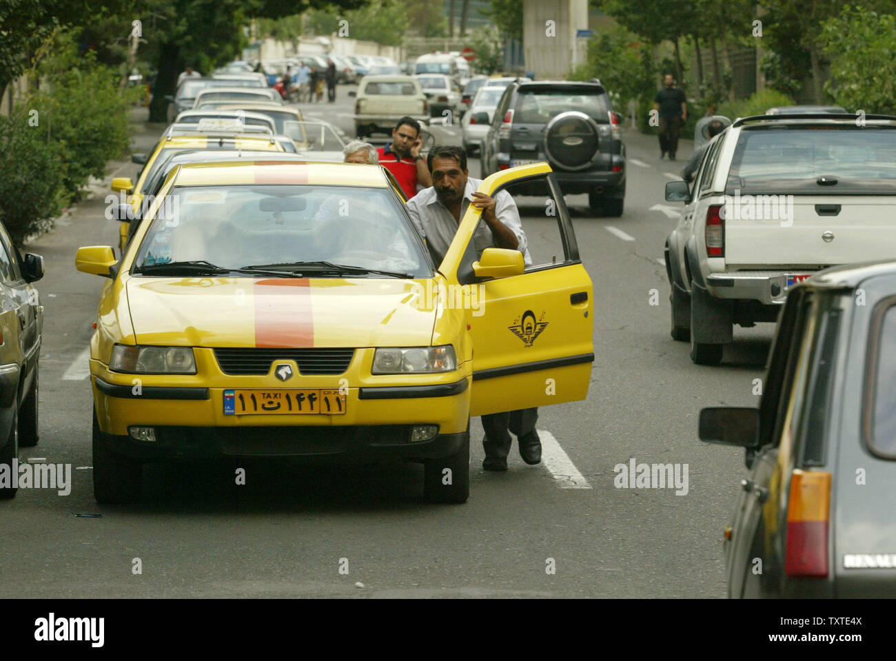 Un chauffeur de taxi iranien pousse sa voiture comme d'autres à attendre en  ligne pour l'essence à Téhéran le 27 juin 2007. L'Iran, le deuxième plus  grand exportateur de pétrole, va commencer