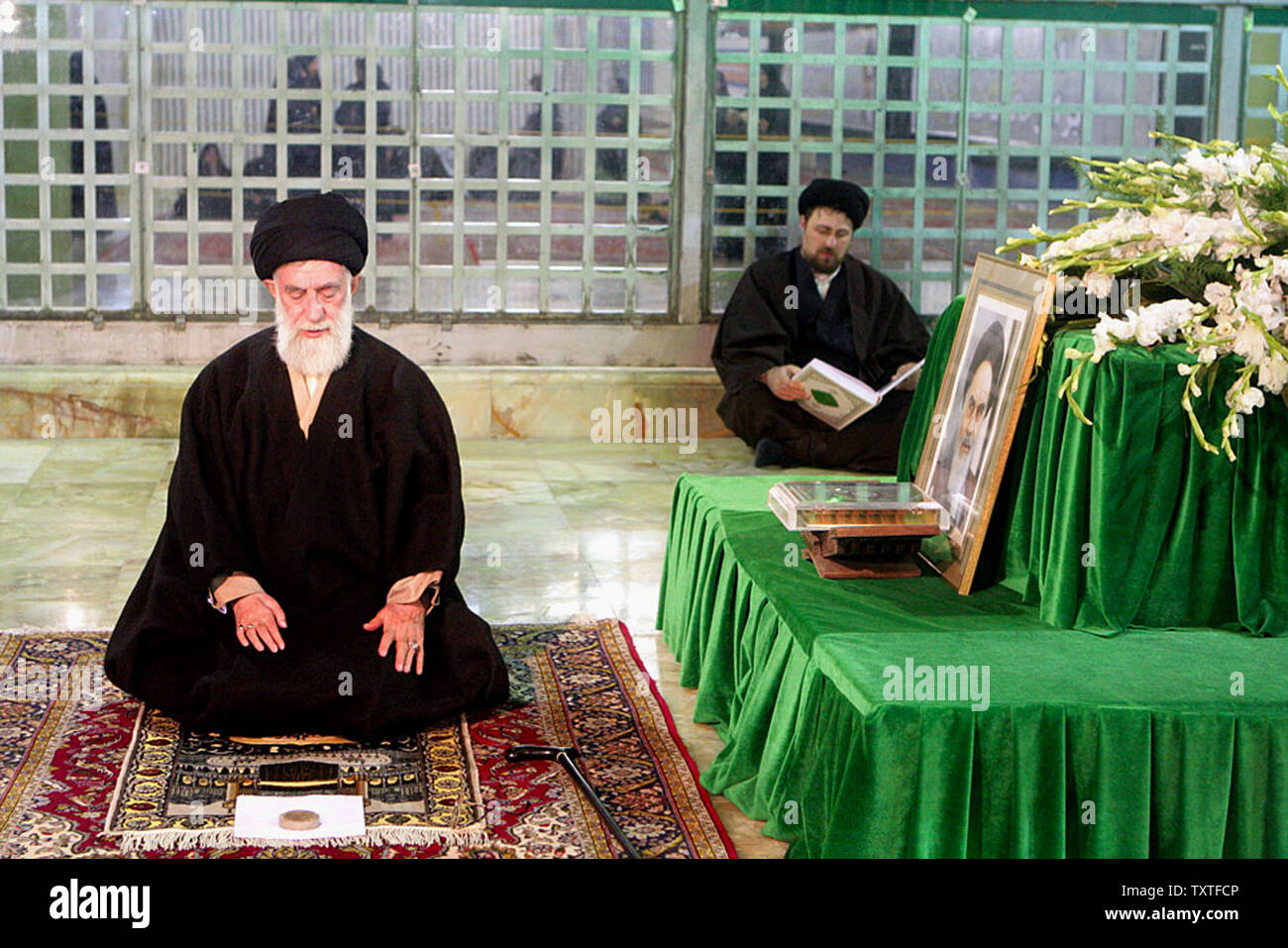 L'Iran l'Ayatollah Ali Khamenei (L) prie pour qu'il visite le sanctuaire de la fin de leader spirituel iranien l'ayatollah Rouhollah Khomeini au mausolée de Khomeiny à Téhéran, l'Iran en janvier 2008. Mostafa Khomeiny, l'Iran a la fin de l'Ayatollah Rohollah le petit-fils de Khomeini est visible sur la droite pendant qu'il lit le Coran. À la veille de l'Assemblée Ten-Day Dawn' les célébrations de la victoire de la révolution islamique, le guide suprême a renouvelé sa fidélité aux idéaux de l'Imam. (Photo/UPI Chef suprême de l'Iran site officiel). . Banque D'Images