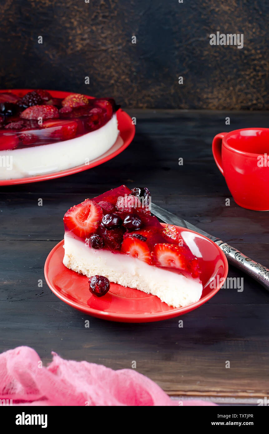 Gâteau mousse à la crème de fruits avec la gelée et les baies fraîches sur la table rustique foncé de délicieux petits fruits rouges frais. La confiture. La vaseline. Le gâteau au fromage. Banque D'Images