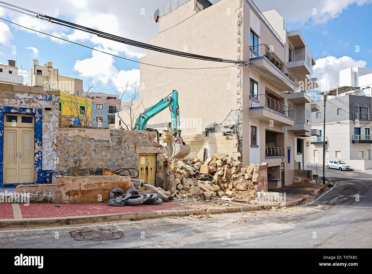 Travailler à la pelle la démolition d'un ancien bâtiment résidentiel parmi d'autres maisons. Les travaux de démolition et d'excavation Banque D'Images