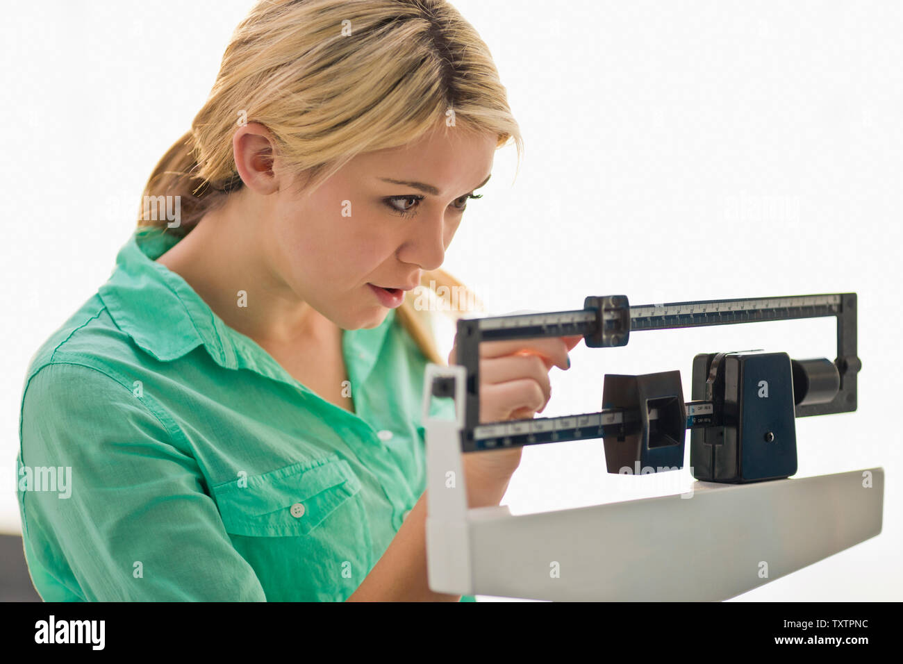 Jeune femme se concentrer alors qu'elle règle la glisser sur une échelle de poids santé. Banque D'Images