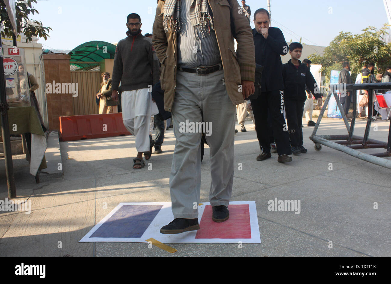 Les partisans du parti islamiste pakistanais Jamaat-ud-Dawa à pied sur le drapeau français à l'entrée d'une mosquée pour exprimer leur colère contre les caricatures religieuses publié par journal satirique français Charlie Hebdo à Islamabad, Pakistan le 16 janvier 2014. Photo par Sajjad Ali Qureshi/UPI Banque D'Images