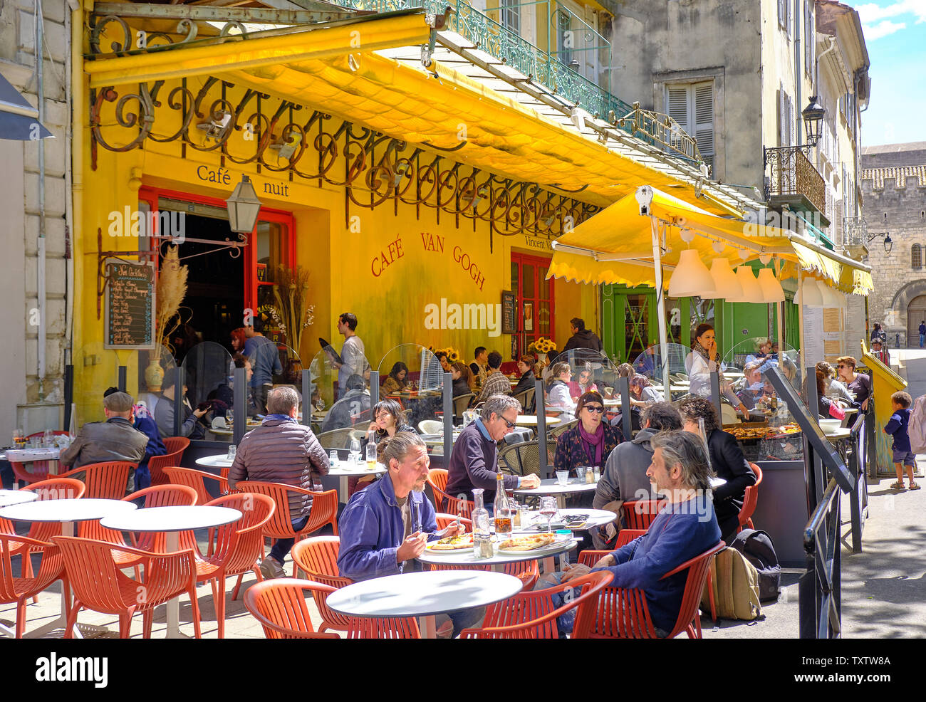 Arles, France : Les visiteurs de la ville boire et manger au Café la nuit, rendue célèbre par Vincent Van Gogh peinture 'terrasse de café de nuit' Banque D'Images