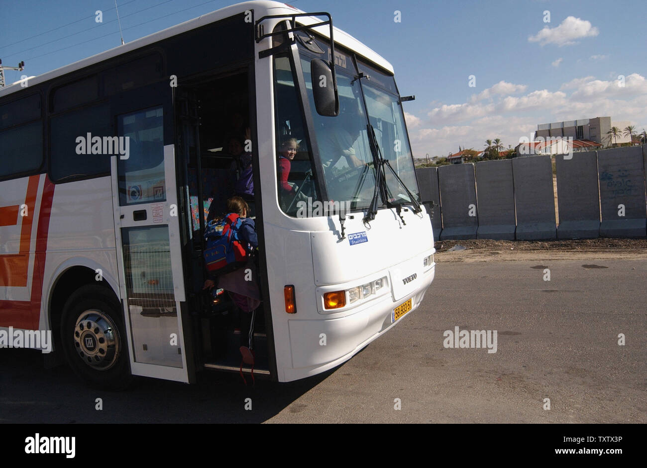 Les enfants israéliens à bord d'un schoolbus avec windows bulletproof près des barrières de protection en béton bordant la zone du terminal de bus à la colonie Neveh Dekalim, 20 novembre 2003. Il y a environ 520 familles de Neveh Dekalim, fondée en 1983. Le Premier Ministre israélien Ariel Sharon a déclaré qu'il permet d'évacuer l'installation d'autres collectivités après avoir rencontré secrètement avec un membre du Conseil de sécurité national des Etats-Unis qui ont demandé à Israël de s'acquitter de sa promesse de démanteler les avant-postes illégaux et de geler leurs activités. (Photo d'UPI/Debbie Hill) Banque D'Images