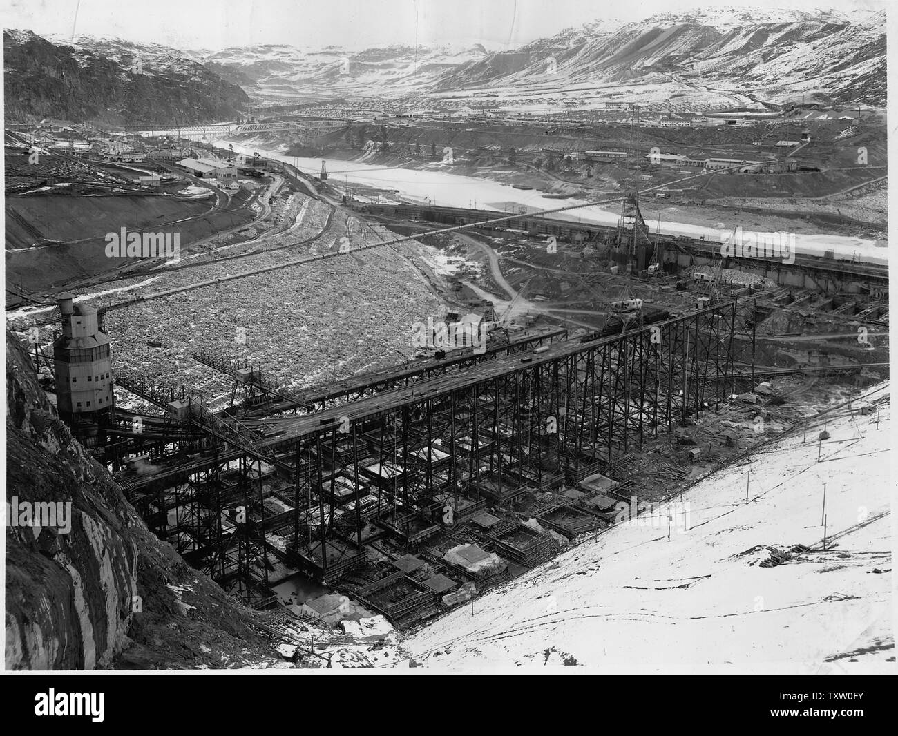 Une vue montrant l'aval la zone ouest après le premier dégel de printemps avec l'état congelé de la rivière encore en preuve. Contreventement bois dans la partie supérieure du bloc 40 se trouve sur la droite. ; Portée et contenu : la photographie de deux volumes d'une série d'albums de photos documentant la construction du barrage de Grand Coulee et travaux connexes sur le bassin du Columbia Projet. Banque D'Images