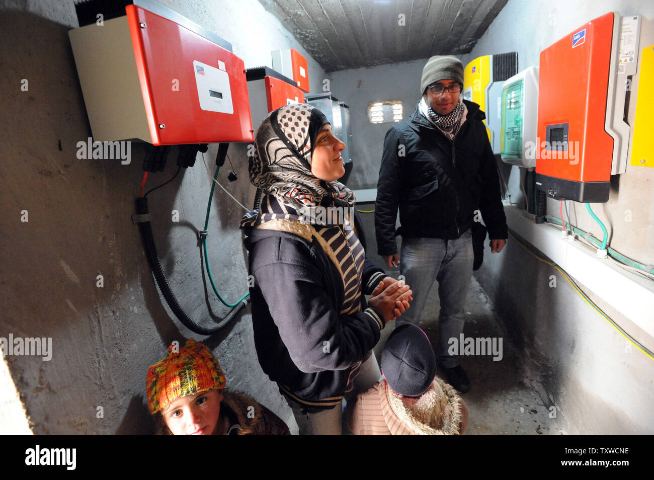 Regardez les Palestiniens des boîtes d'électricité facturés par des panneaux solaires et éoliennes dans l'Elle El-Buttum b village dans les collines au sud d'Hébron, en Cisjordanie, le 29 février 2012. L'Administration civile israélienne a émis des ordres de démolition pour les installations d'énergie renouvelable de panneaux solaires et éoliennes qui fournissent l'électricité aux Palestiniens qu'Israël refuse de raccorder au réseau d'électricité. Les installations de l'énergie ont été payées par le ministère allemand des Affaires étrangères et à l'initiative de bénévoles israéliens. L'électricité par les panneaux solaires et éoliennes a révolutionner Banque D'Images