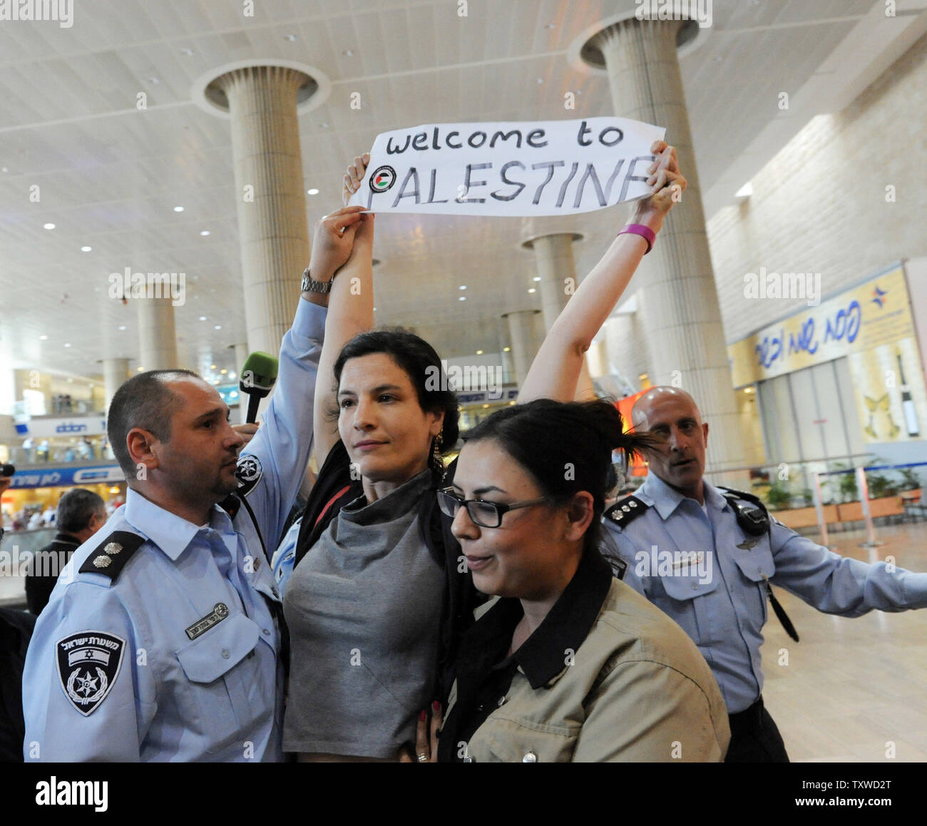 Une policière secrètes israéliennes (R) arrête une activiste de gauche tenant un slogan pro-Palestiniens à l'aéroport Ben Gourion, près de Tel-Aviv, le 15 avril 2012. Des centaines de policiers israéliens, beaucoup d, ont été déployés à l'aéroport pour bloquer l'arrivée de militants pro-palestiniens de prendre part à une 'Bienvenue à la Palestine' fly-in. Alors Israël pour empêcher l'entrée de militants, les compagnies aériennes étrangères d'avertissement qu'ils seraient forcés de payer la facture pour le retour immédiat des militants accueil. UPI/Debbie Hill Banque D'Images