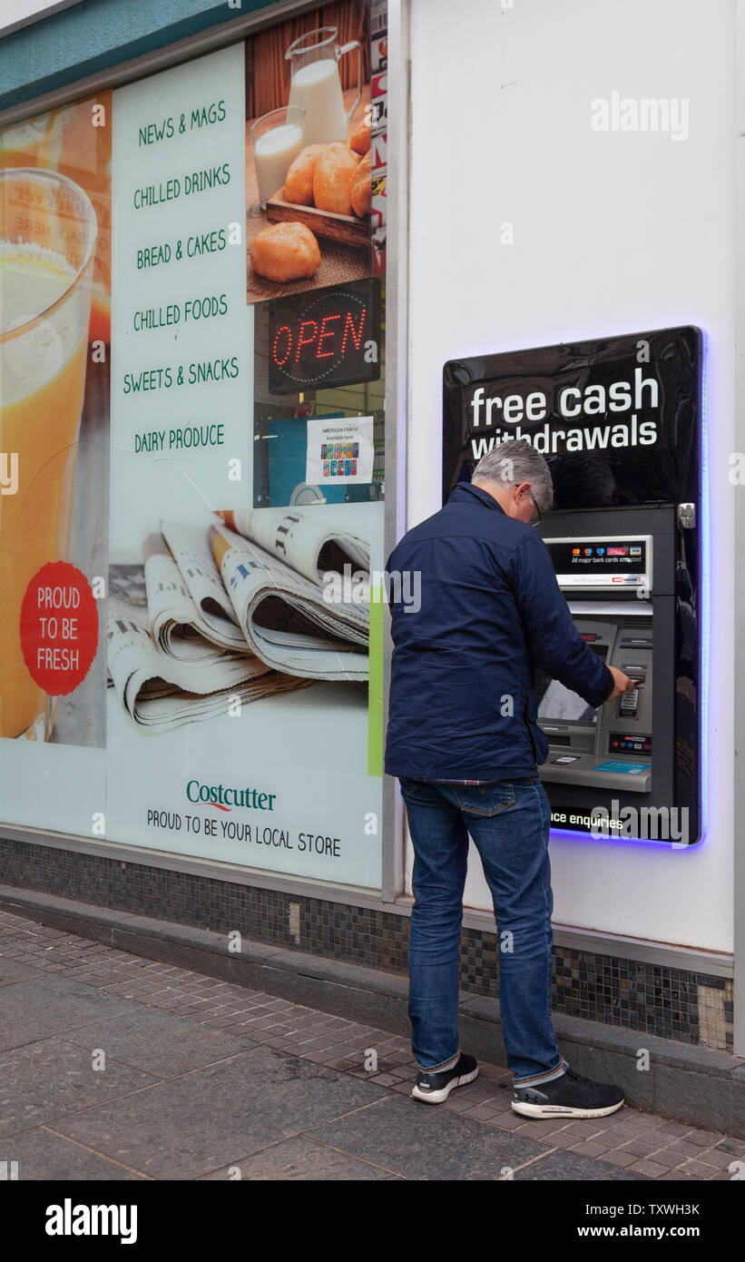 L'homme de l'argent dans un distributeur / un point à l'extérieur un Costcutter shop à Stirling, Ecosse, Royaume-Uni Banque D'Images
