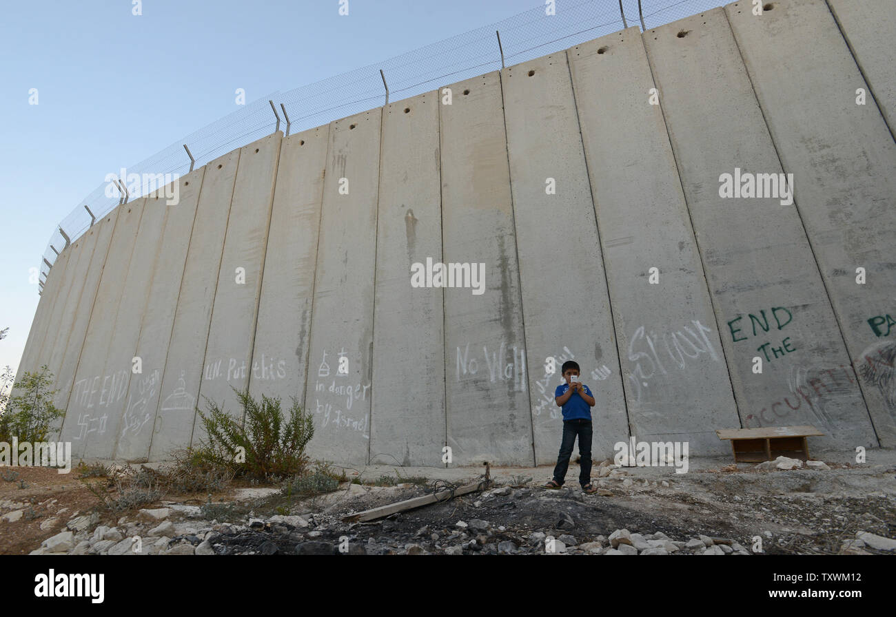 Un garçon palestinien prend une photo avec son portable devant le mur de séparation israélien d'Abu Dis en Cisjordanie, le 29 septembre 2014. Le Premier ministre israélien Benjamin Netanyahu n'a pas parlé d'un futur Etat palestinien dans son discours à l'Assemblée générale des Nations Unies aujourd'hui à New York. UPI/Debbie Hill Banque D'Images