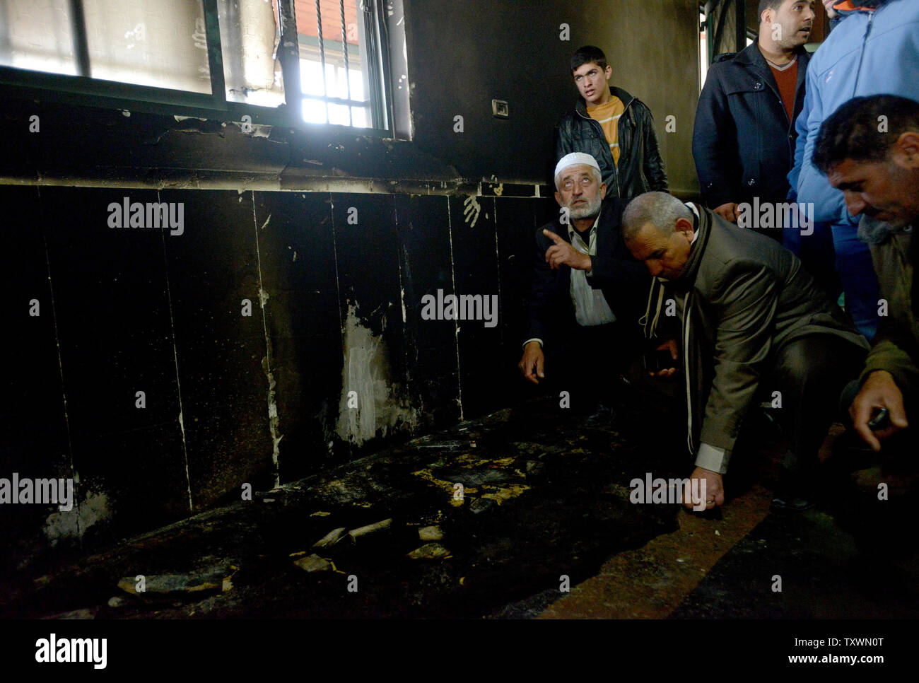 Palestiniens inspecter les dommages à l'intérieur d'une mosquée qui a été incendié et aspergés de graffitis dans un 'tag' prix attaque la haine par des colons juifs extrémistes à Al Jaba'ah, près de Bethléem, en Cisjordanie, le 25 février 2015. Les résidents palestiniens disent qu'ils ont vu des colons israéliens près de la mosquée lorsqu'il a été attaqué tôt mercredi matin. Une étoile de David et 'Vengeance' et 'Nous voulons que la rédemption de Sion" ont été peints à l'extérieur de la mosquée. Photo par Debbie Hill/UPI Banque D'Images