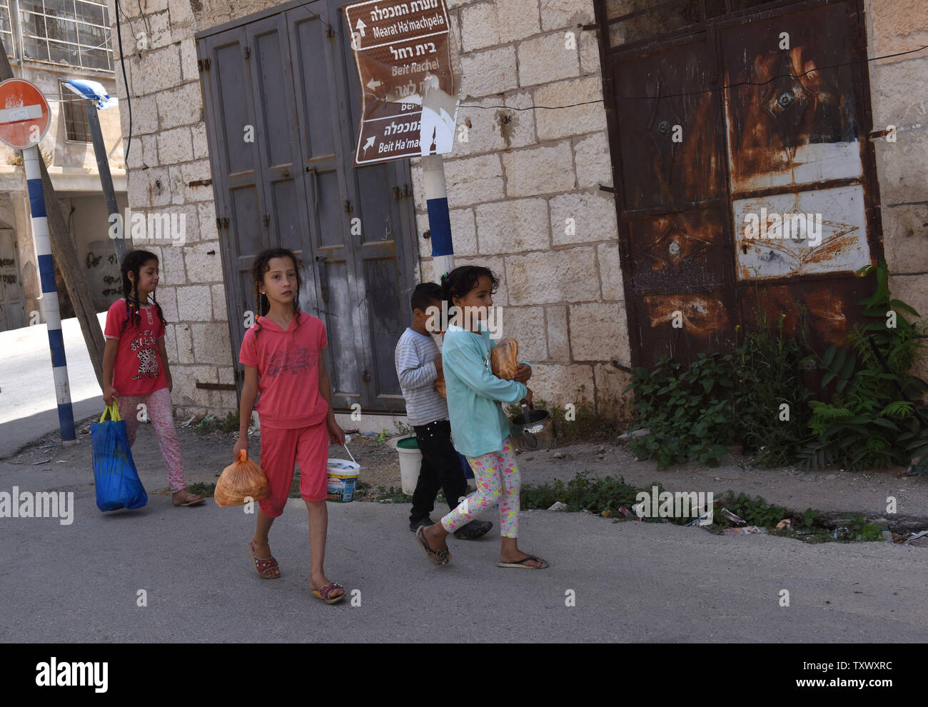 Les enfants palestiniens porter la nourriture à la maison d'une soupe populaire dans la ville divisée de Hébron, en Cisjordanie, le 6 juillet 2017. Les diplomates palestiniens sont à la recherche d'une reconnaissance de la vieille ville d'Hébron, qui comprend la grotte des Patriarches, au patrimoine mondial de l'UNESCO. Le vote aura lieu le vendredi 7 juillet, lors d'une réunion du Comité du patrimoine mondial de l'Unesco à Cracovie, Pologne, environ 800 colons juifs nationalistes vivent parmi plus de 100 000 Palestiniens dans la vieille ville d'Hébron. Photo par Debbie Hill/UPI Banque D'Images