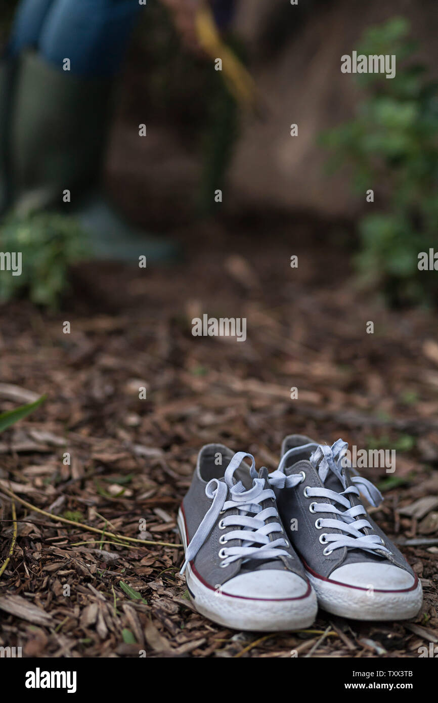 Adulte portant des bottes de Wellington vert olive (bottes de wellies) plantant des plantes succulentes dans l'arrière-cour de sa maison. Banque D'Images