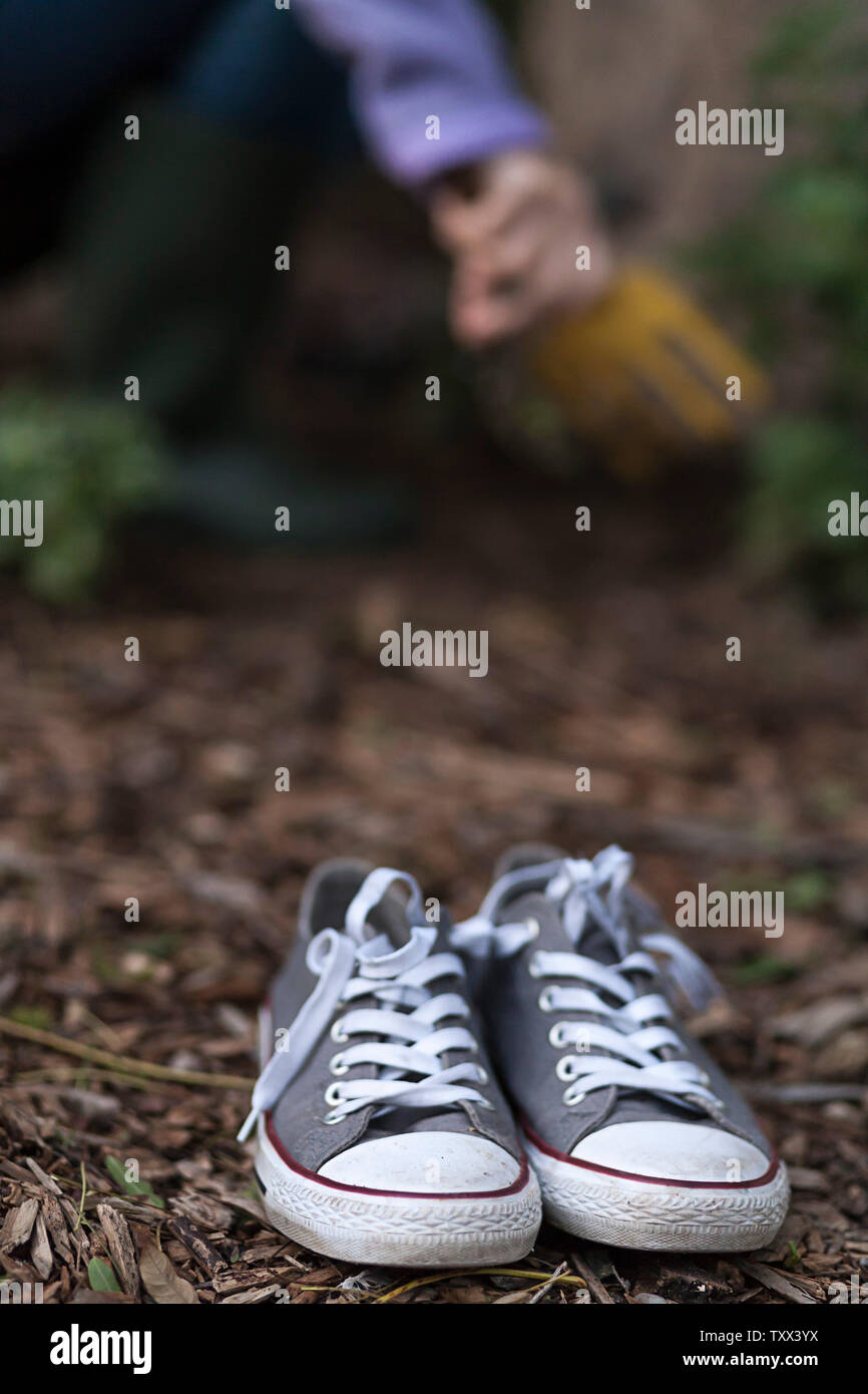 Adulte portant des bottes de Wellington vert olive (bottes de wellies) plantant des plantes succulentes dans l'arrière-cour de sa maison. Banque D'Images