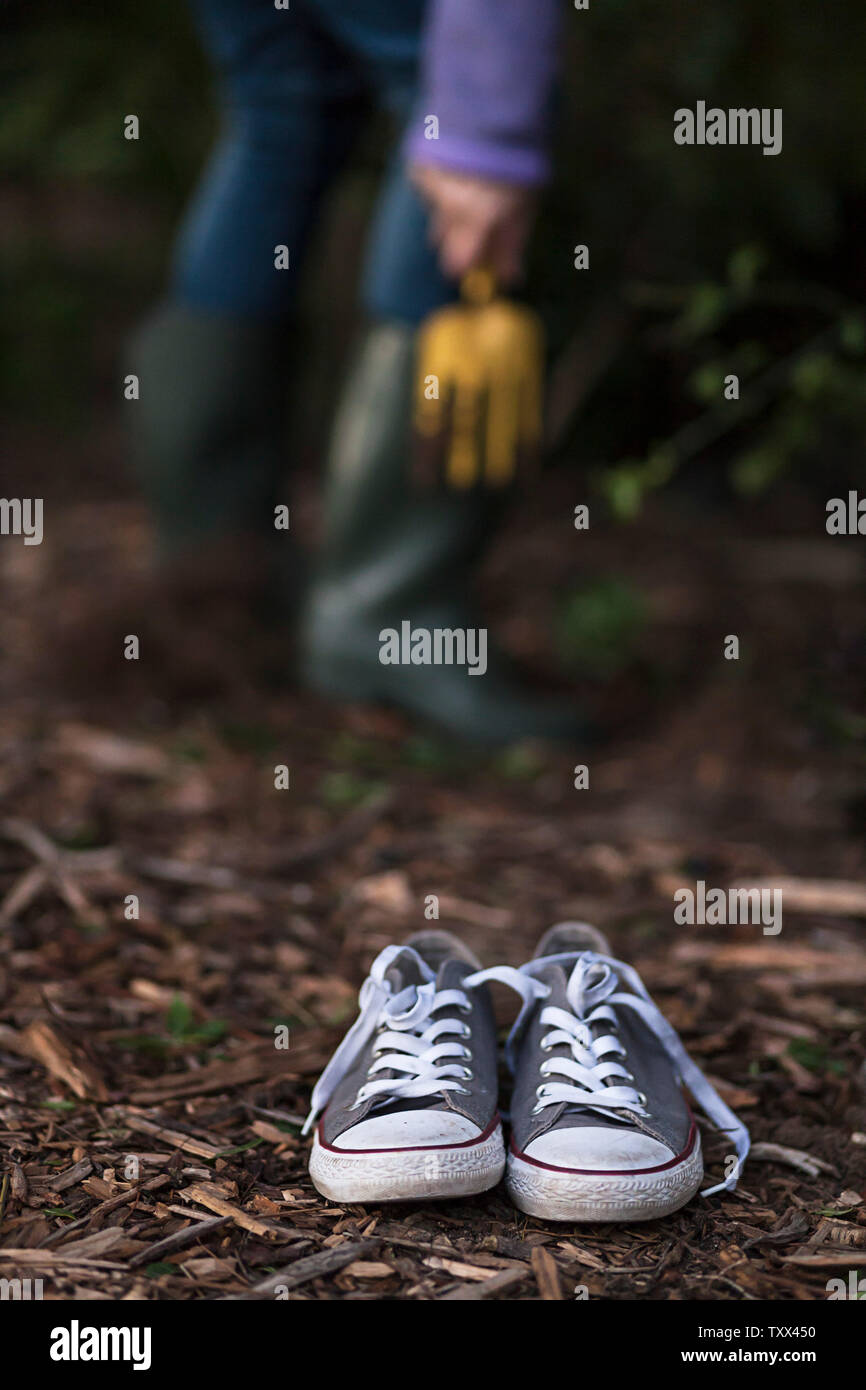 Adulte portant des bottes de Wellington vert olive (bottes de wellies) plantant des plantes succulentes dans l'arrière-cour de sa maison. Banque D'Images