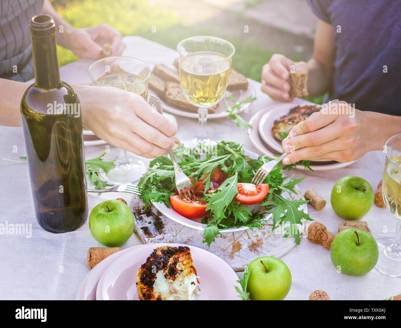 Les gens mangent dans le jardin à la table. Le dîner avec vin concept dans l'air frais. Poissons de mer grillés et des salades de légumes et d'herbes. Méditerranée Banque D'Images