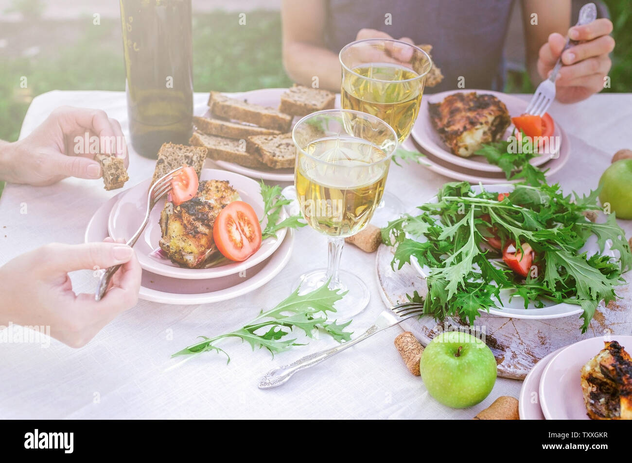 Les gens mangent dans le jardin à la table. Le dîner avec vin concept dans l'air frais. Poissons de mer grillés et des salades de légumes et d'herbes. Méditerranée Banque D'Images