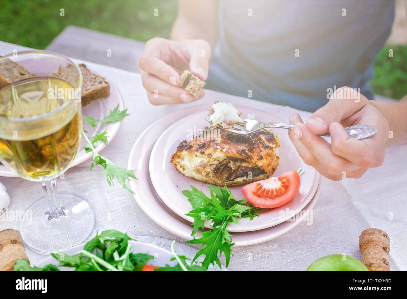 L'homme de manger du poisson de mer frits dans le jardin à la table. Le dîner avec vin concept dans l'air frais. Le poisson et les salades de légumes et d'herbes. Mediterran Banque D'Images