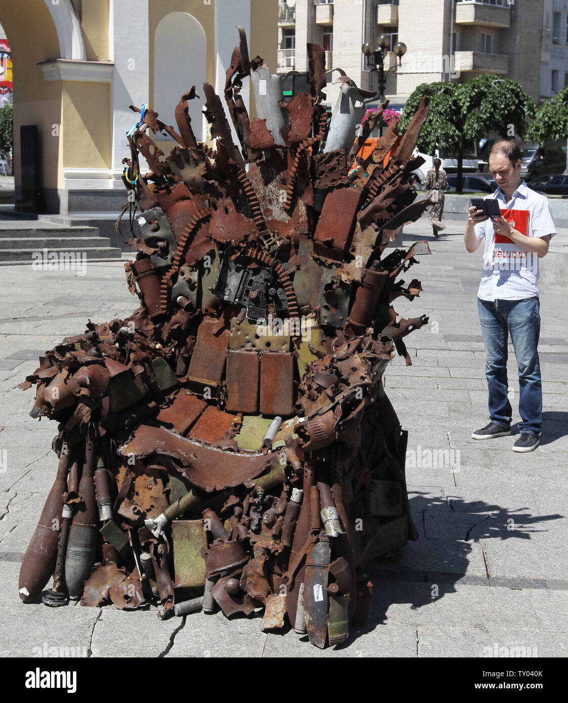 25 juin 2019 - Kiev, Ukraine - un homme prend une photo de l'album 'Le Trône de fer de l'Est' d'art, qui a présenté sur la place de l'indépendance, à Kiev, Ukraine, le 25 juin 2019. "Le trône de fer de l'Est' a été créé un bénévole ukrainienne fighter Denis Bushtets dans la zone de conflit de la guerre dans l'Est de l'Ukraine près de Donetsk en 2016. L'objet d'art est faite à partir de l'épave de l'armure du réservoir, parties de démoli le matériel militaire, mitrailleuses, obus, cartouches et flacons du soldat et il n'est plus de 600 kg de poids. Un prototype d'un célèbre discours du Trône de fer Game of Thrones série TV est un rappel d'un bl Banque D'Images