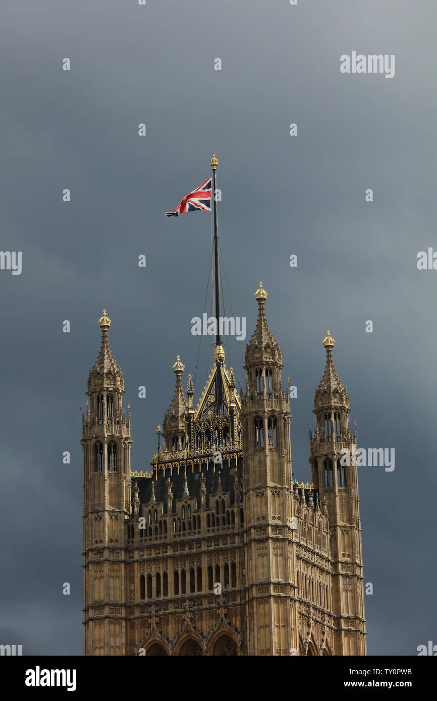 Haut de tour avec un mât et l'Union Jack au soleil contre un ciel gris à Londres, dans l'après-midi au mois de juin. Banque D'Images