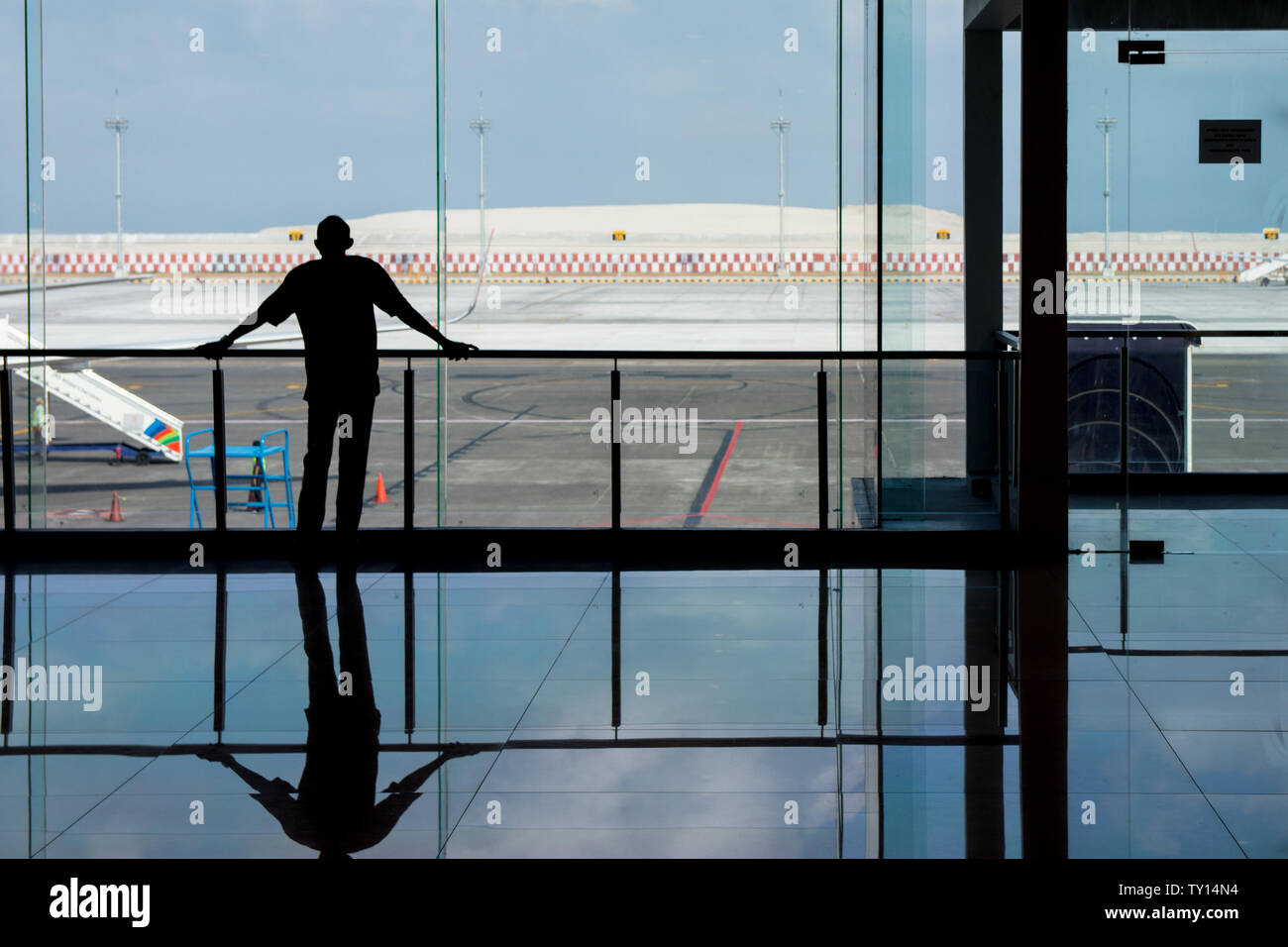 Denpasar, Bali, Indonésie : 05 juin 2019 - l'homme à la recherche au travers de fenêtres à l'aéroport, car il attend que son avion. Banque D'Images