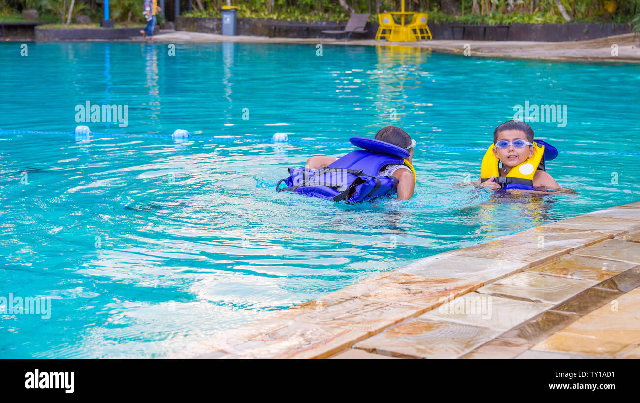 Garçon de natation avec gilet et sur googles à piquer sa langue à la recherche très heureux. Banque D'Images