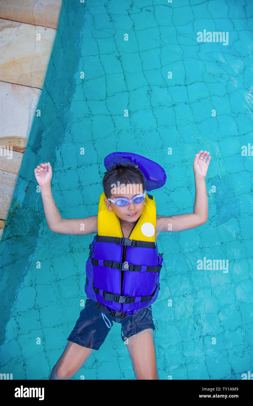 Garçon de natation avec gilet et sur googles à piquer sa langue à la recherche très heureux. Banque D'Images