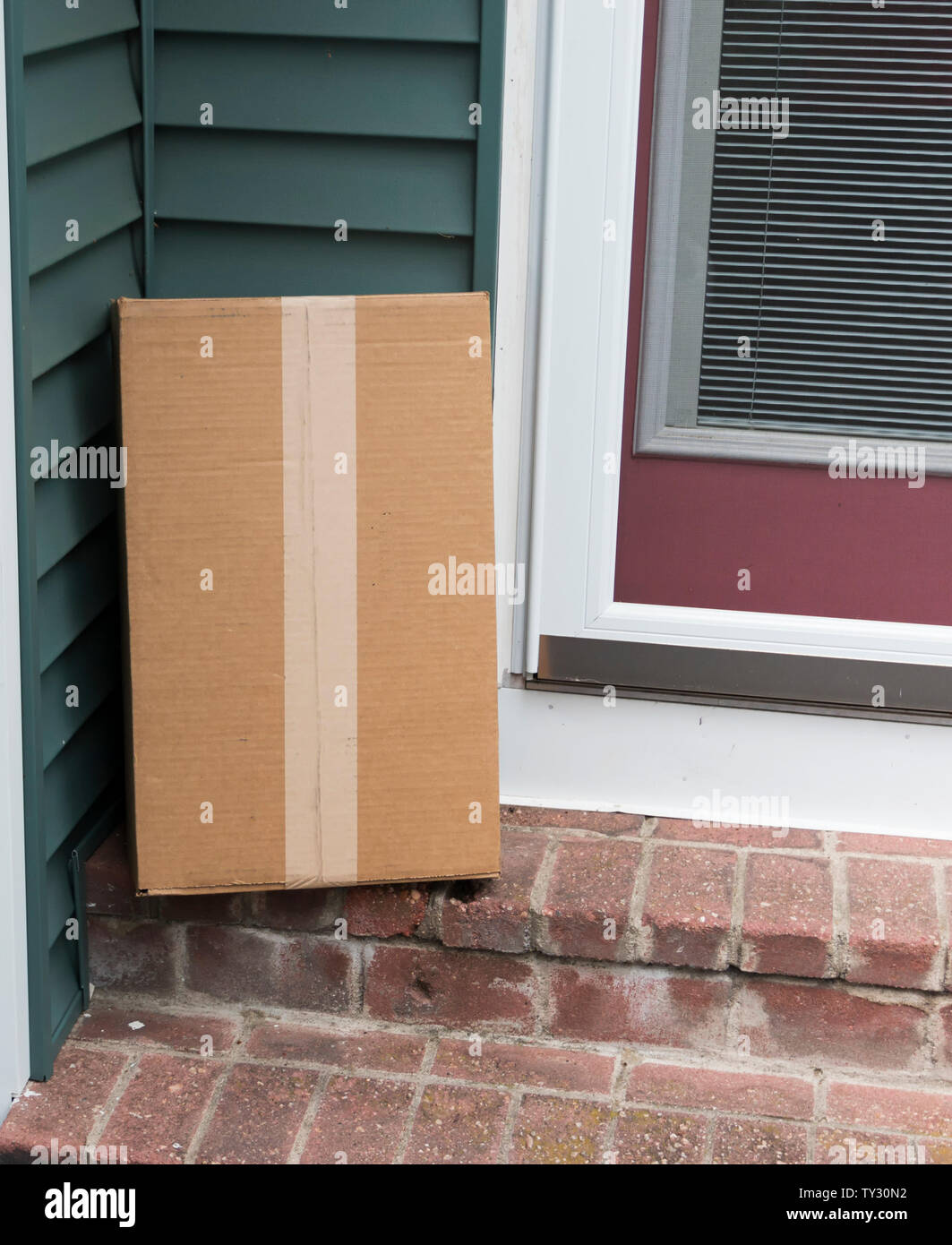 Une boîte en carton brun est livré à la porte du côté d'un immeuble d'accueil. Banque D'Images