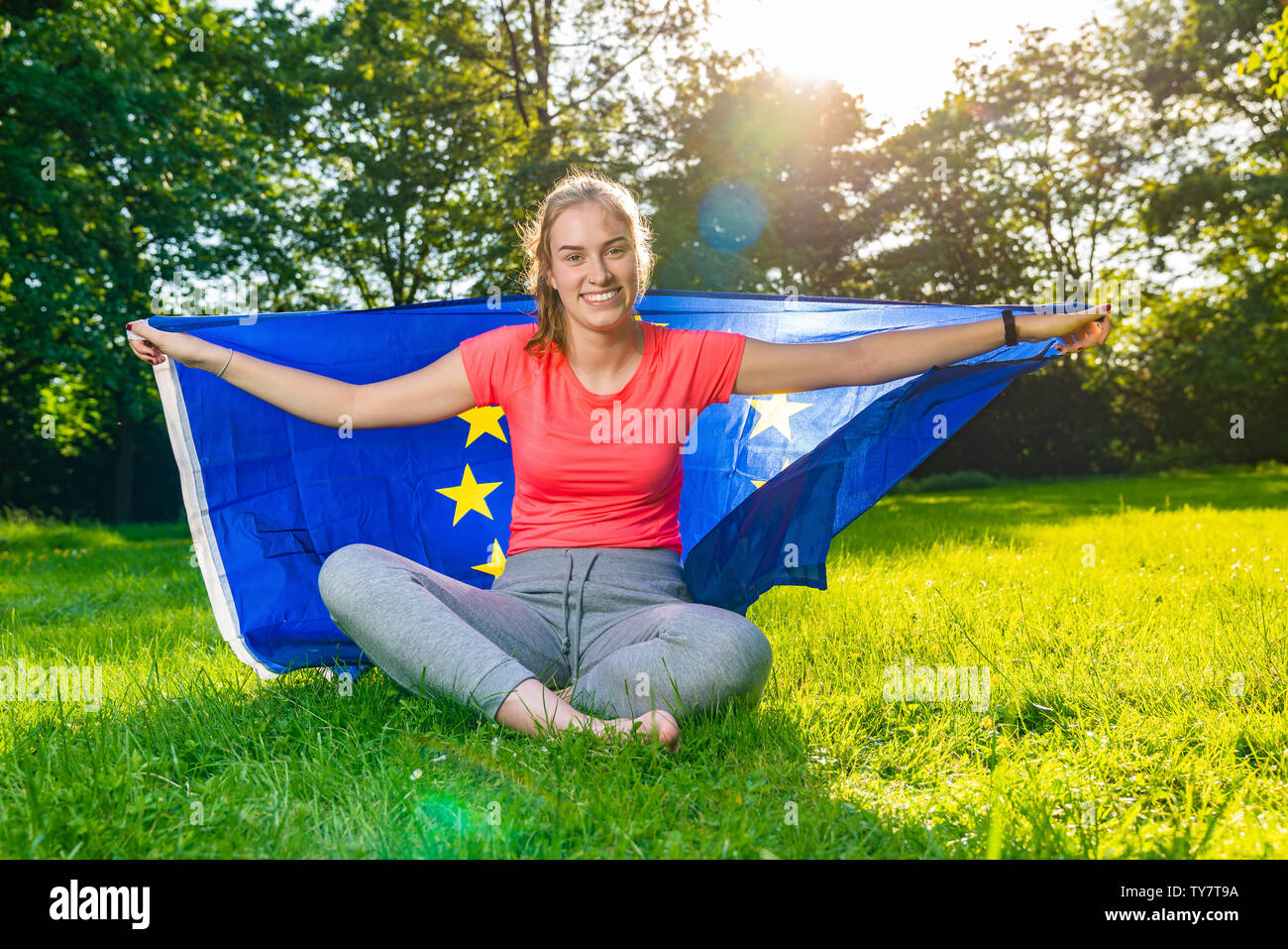 Jeune femme porte un drapeau européen derrière et sourit Banque D'Images