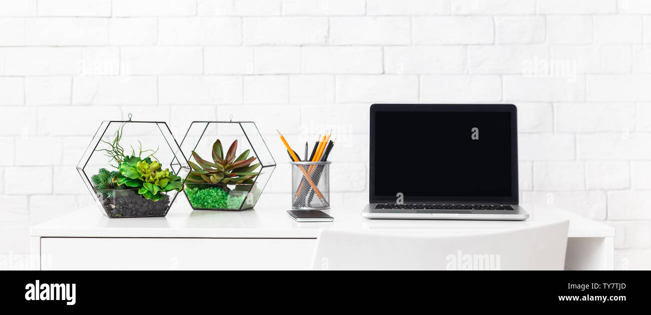 Lieu de travail à la maison moderne avec un ordinateur portable, et les plantes d'arrière-plan blanc au mur de brique Banque D'Images