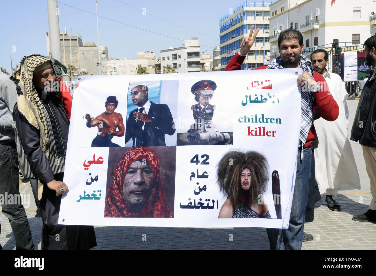 Libyens tenir photos montrant Mouammar Kadhafi et son fils Saif dans une manière péjorative lors des funérailles de deux rebelles l'un d'eux Faraj Omar Boushaiha, 51 ans, qui a dit de sa famille est mort à Ajdabiya, lors de ses funérailles le Jeudi, Avril 15, 2011, dans la place à côté du palais de justice sur la corniche à Benghazi, en Libye. UPITarek Alhuony. Banque D'Images