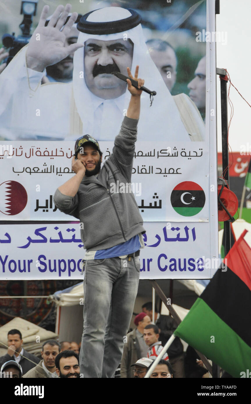 Un libyens clignote un V en regard d'une affiche de l'Emir du Qatar, Cheikh Hamad bin Khalifa al-Thani comme son assiste à un rassemblement contre le dirigeant libyen Mouammar Kadhafi à Benghazi, en Libye, le 28 avril 2011. UPITarek Alhuony. Banque D'Images
