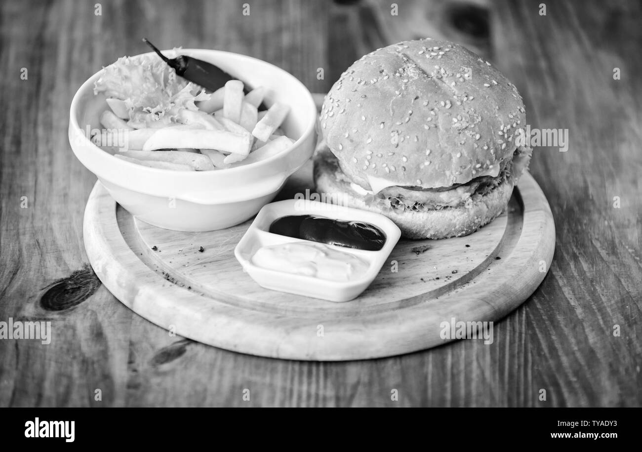 Menu Burger. Des calories. Hamburger et frites et de la sauce tomate sur planche de bois. Concept de restauration rapide. Burger de viande avec du fromage et de la salade. Repas de triche. Burger délicieux avec des graines de sésame. Banque D'Images