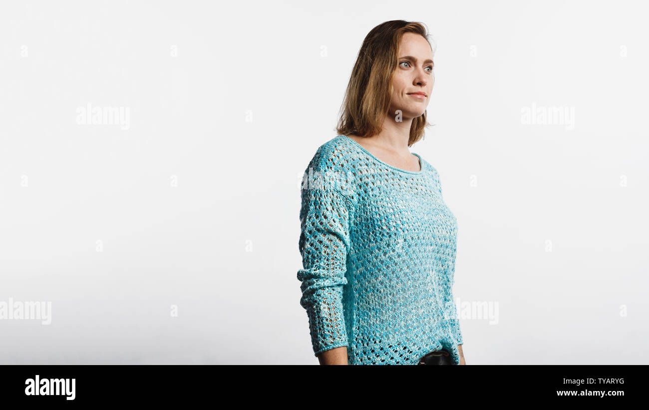 Vue latérale d'une femme en haut laine standing against white background. Femme aux cheveux bruns courts à la route. Banque D'Images