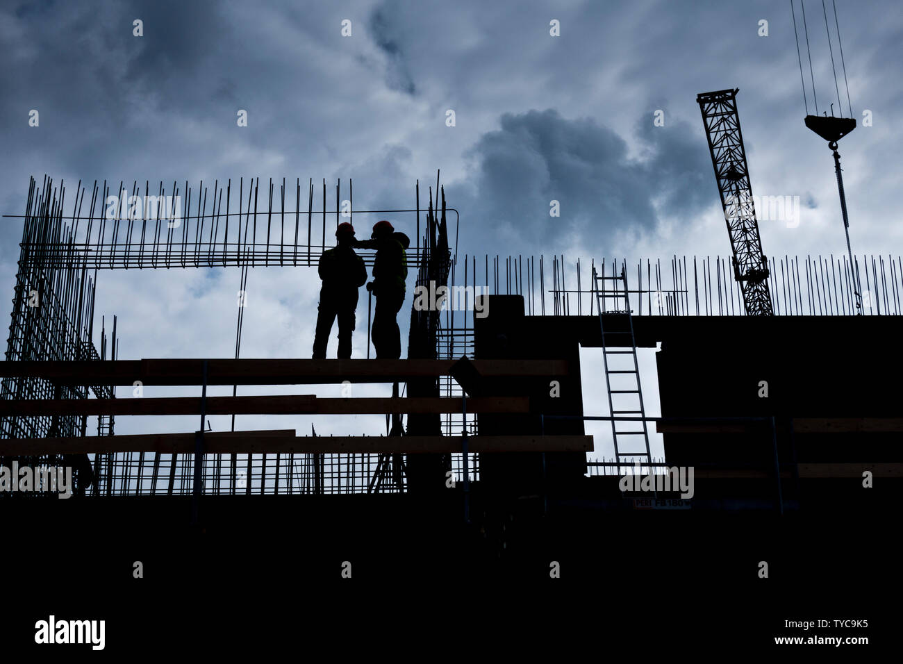 Silhouette de deux travailleurs sur le haut d'un immeuble en construction Banque D'Images