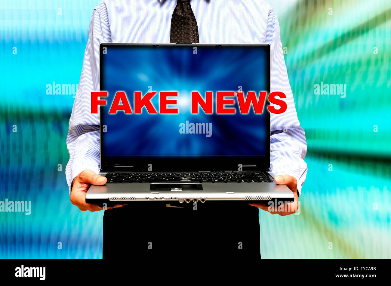 Homme tenant un ordinateur portable avec des mots faux news à l'écran Banque D'Images