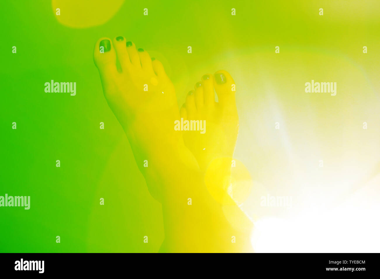Une paire du pied sur un fond de couleur vert jaune avec un effet de halo. Le concept créatif de brochure ou d'autres idées Banque D'Images