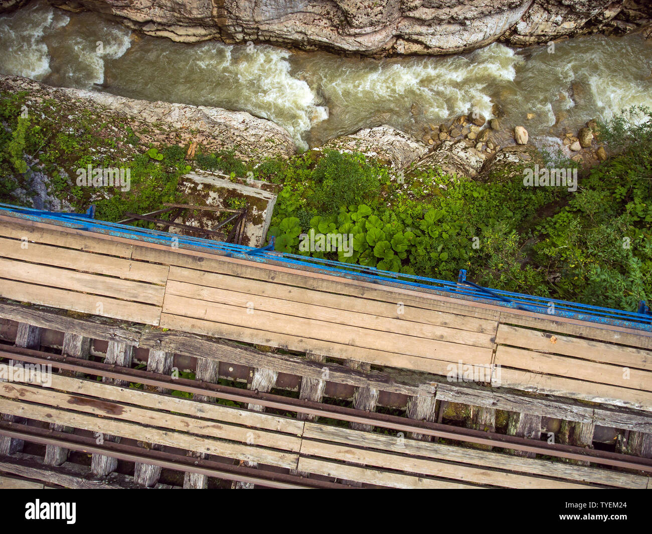 Vue de dessus du pont en bois avec voie étroite. Des rapides sur un ruisseau de montagne dans les roches. Banque D'Images