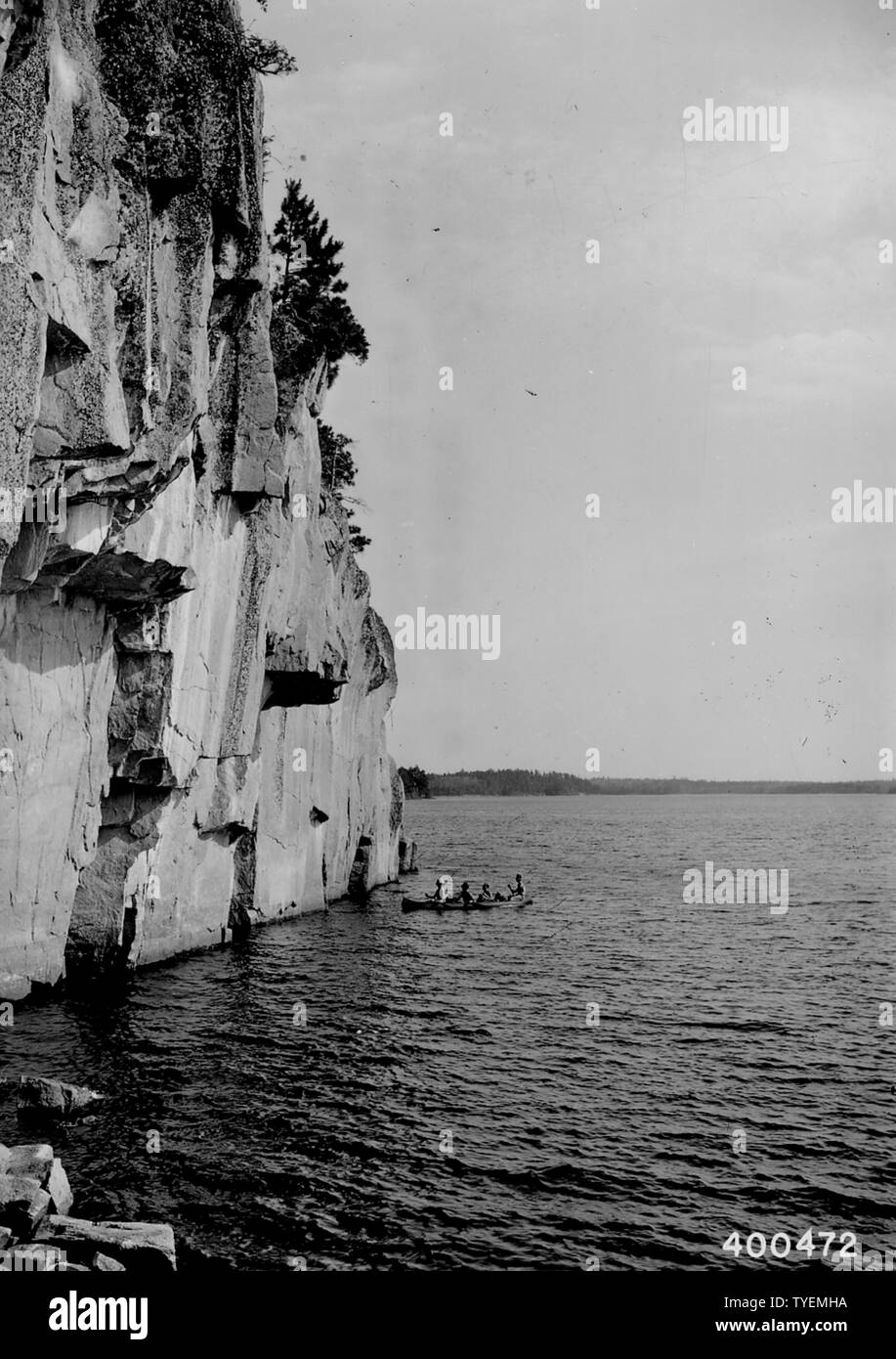 Photographie d'une partie de quatre campeurs dans un canot ; Portée et contenu : la légende originale : une partie de quatre campeurs dans un canoë à la base de la falaise de la Roches Peintes, Lac La Croix sur la frontière internationale. Banque D'Images