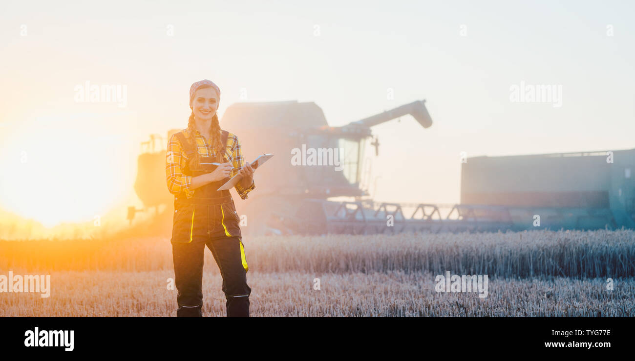 Femme d'agriculteurs et de moissonneuse-batteuse, sur champ de blé Banque D'Images Femme d'agriculteurs et de moissonneuse-batteuse, sur champ de blé Banque D'Images