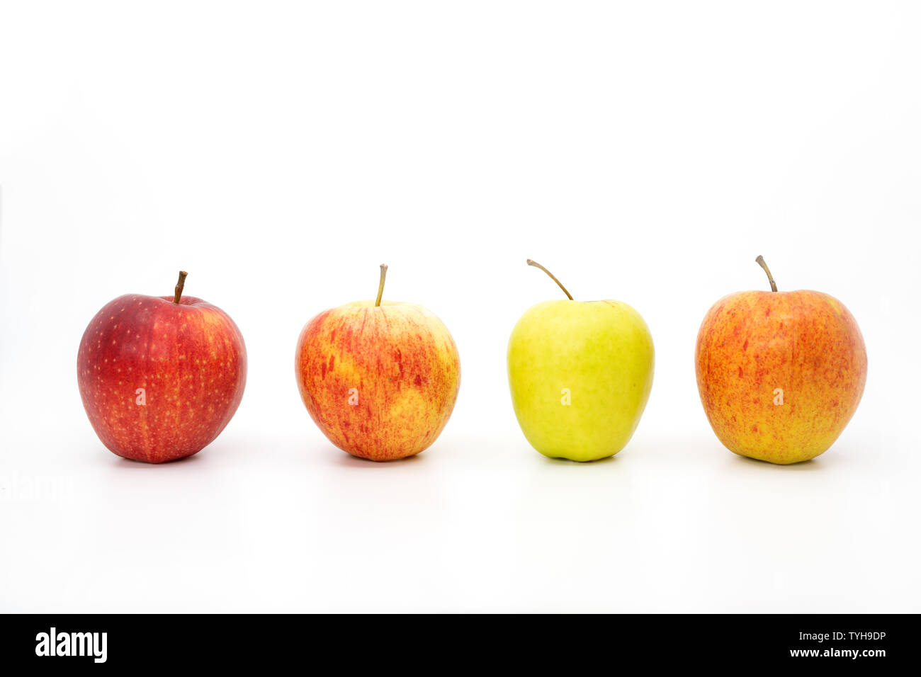 Quatre pommes dans une rangée avec trois pommes rouges et une pomme verte Banque D'Images