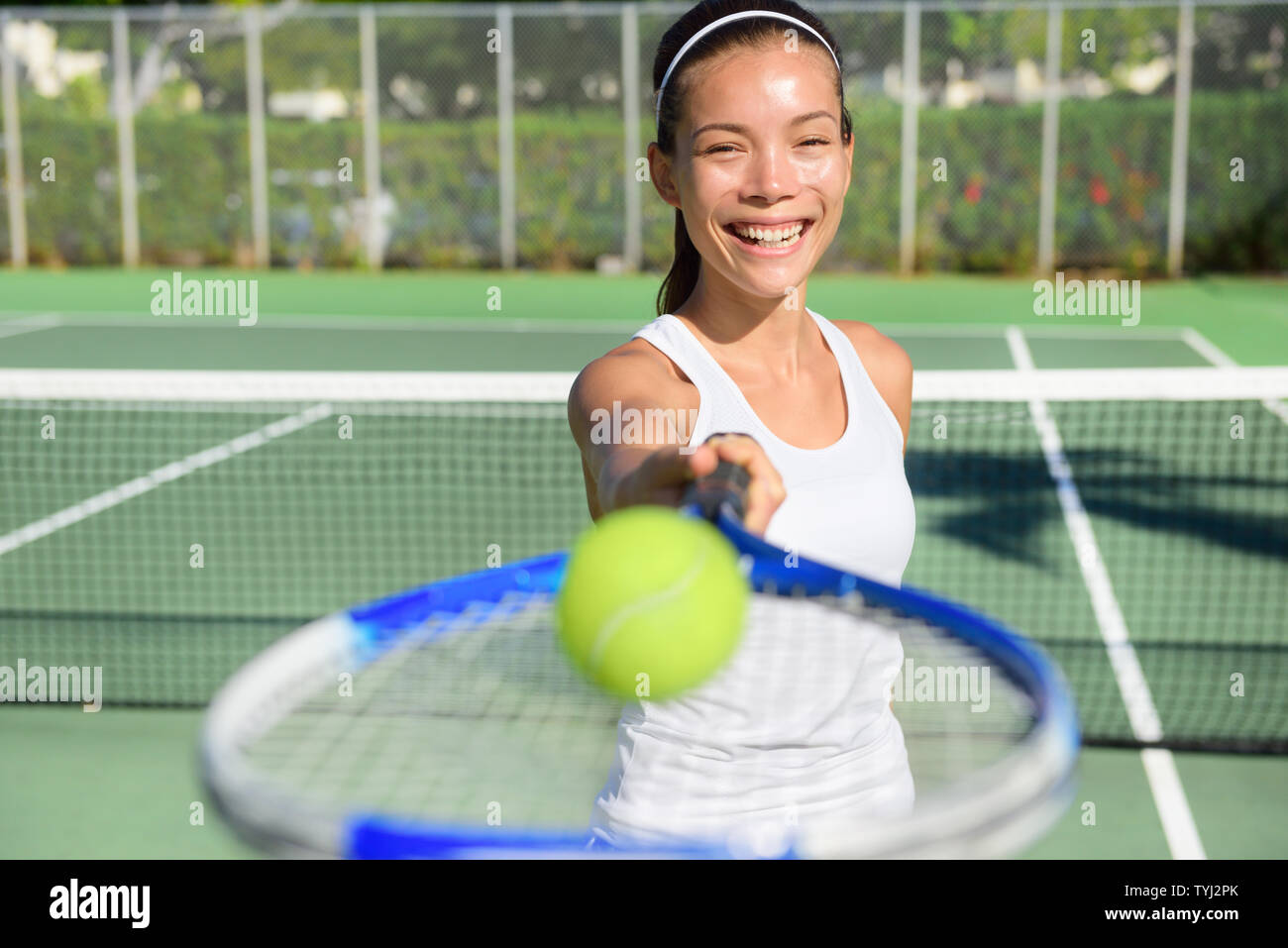 Portrait de joueur de tennis. Femme montrant balle de tennis racket smiling happy. Athlète féminin vous invite à jouer au tennis. Active en bonne santé et sport de plein air concept de vie de forme physique. Banque D'Images