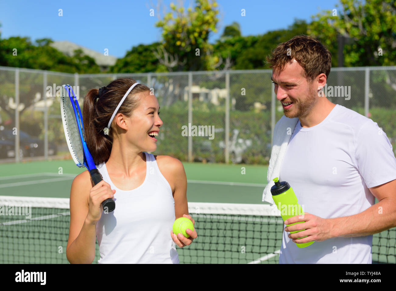 Sport Tennis - young après avoir joué au tennis à l'extérieur en été. Happy smiling friends sur tennis extérieur sain vivant de vie de forme physique active. La femme et l'homme les athlètes. Banque D'Images