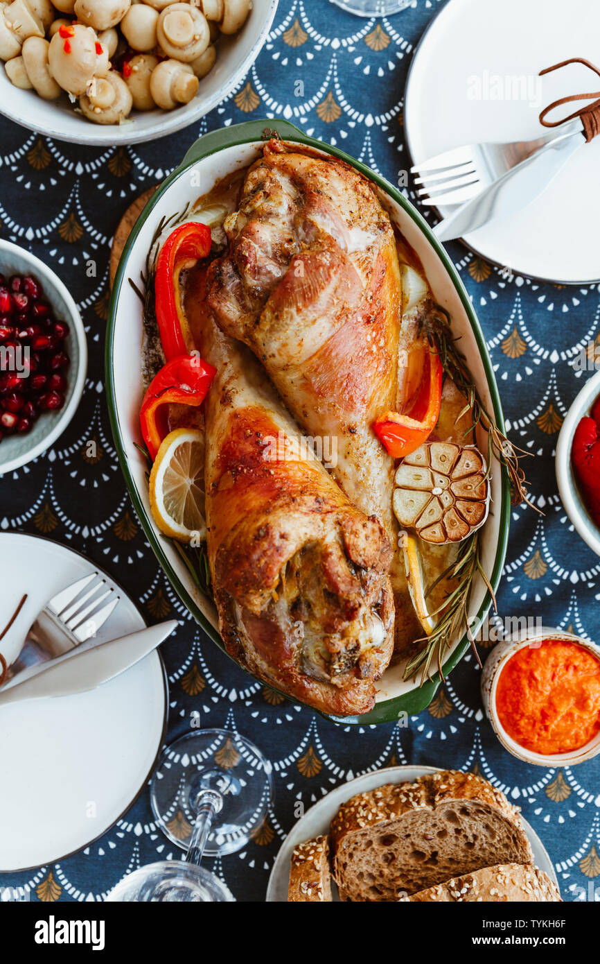 Plat de fête pour Thanksgiving, rôti de dinde jambes avec des légumes sur une table avec des collations. Banque D'Images