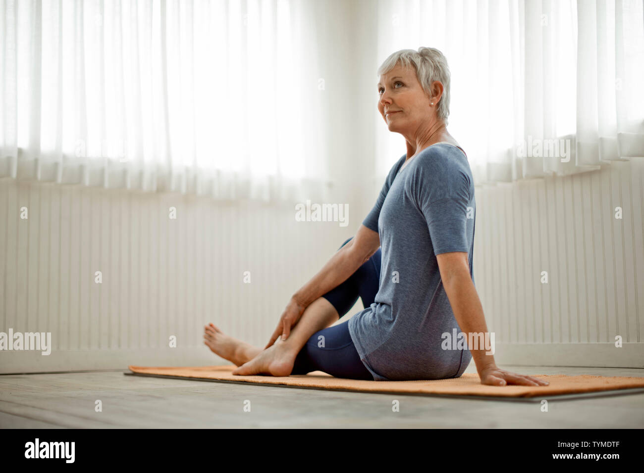 Femme mature pacifiques pratiques étirements de yoga dans son home studio. Banque D'Images