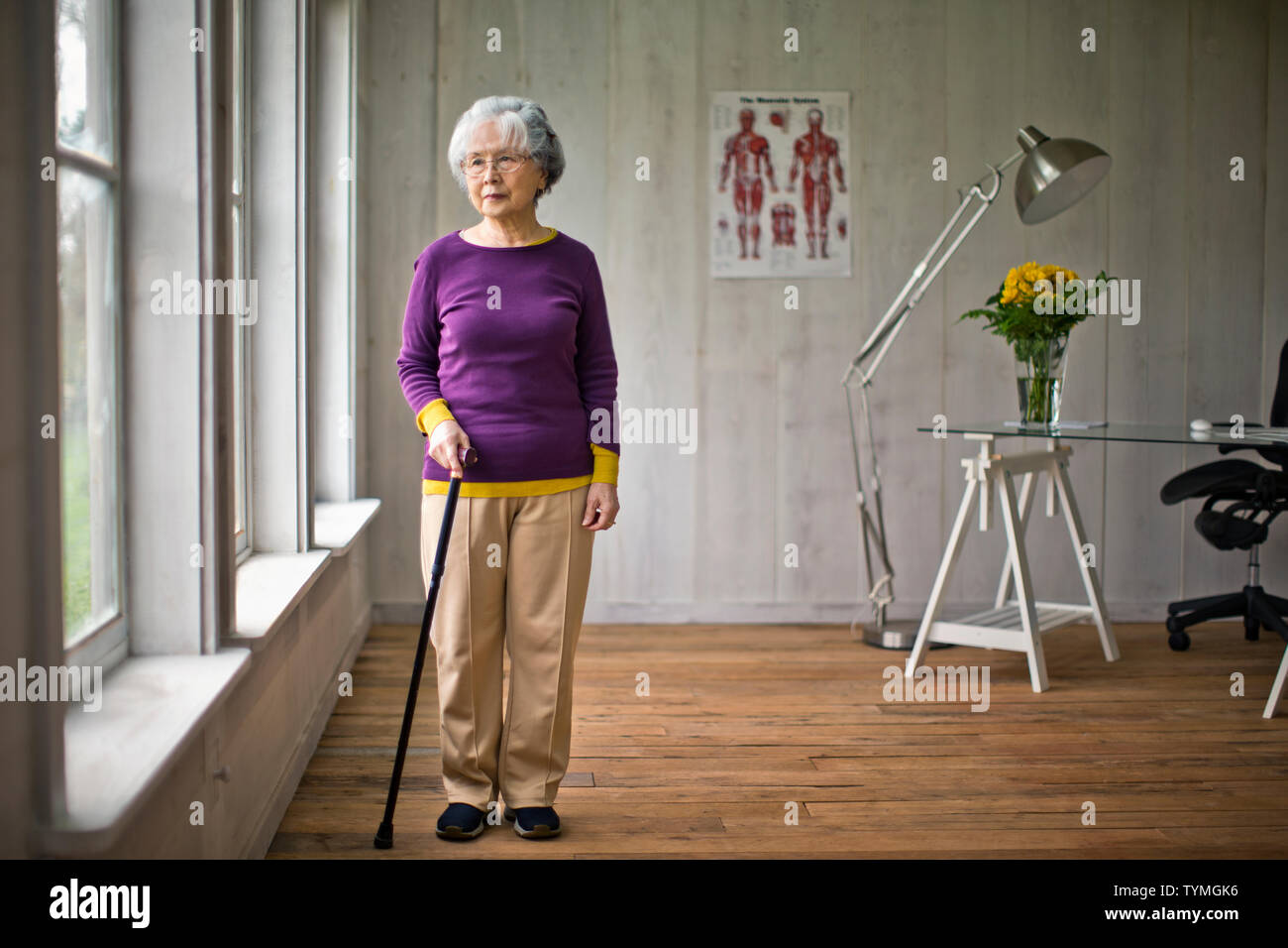 Senior woman looking out de la fenêtre dans le bureau du médecin. Banque D'Images