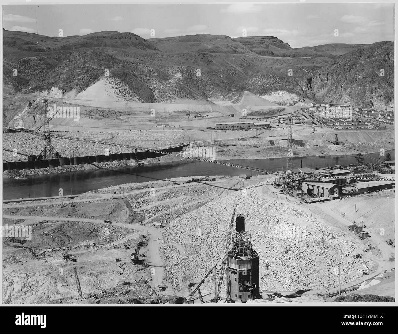 Trois-panorama du haut du pilier. Le Eastmix usine de béton en construction apparaît au centre premier plan. ; Portée et contenu : la photographie de deux volumes d'une série d'albums de photos documentant la construction du barrage de Grand Coulee et travaux connexes sur le bassin du Columbia Projet. Notes générales : Cette image fait partie d'une vue panoramique qui comprend les articles 1007, 1007-A, et 1007-B. L'image d'origine mesure environ 22 pouces de largeur. Banque D'Images