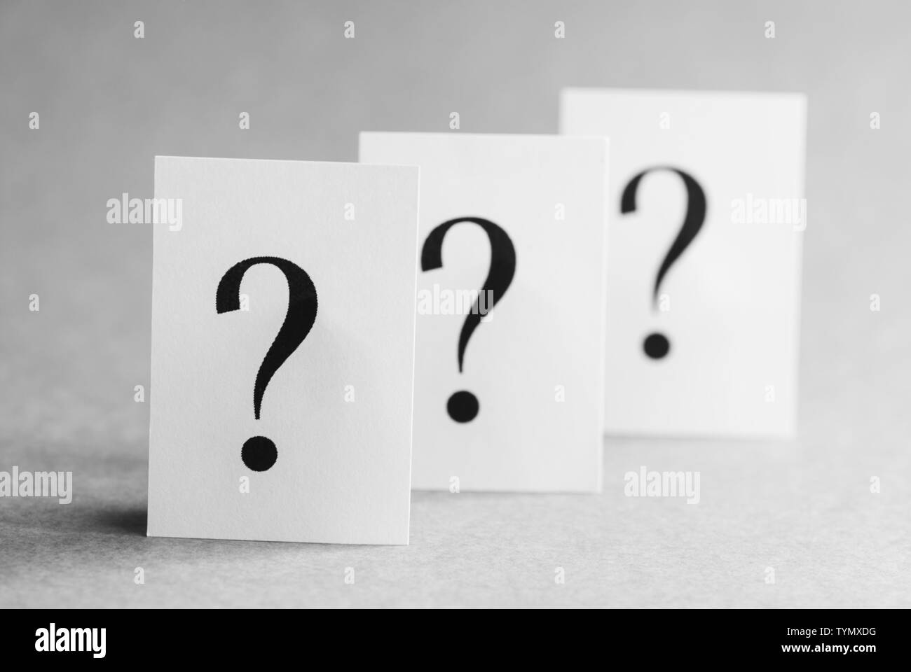 Trois points d'interrogation imprimé sur des cartes blanches disposées dans une ligne diagonale de recul avec l'accent de l'un à l'avant-plan Banque D'Images