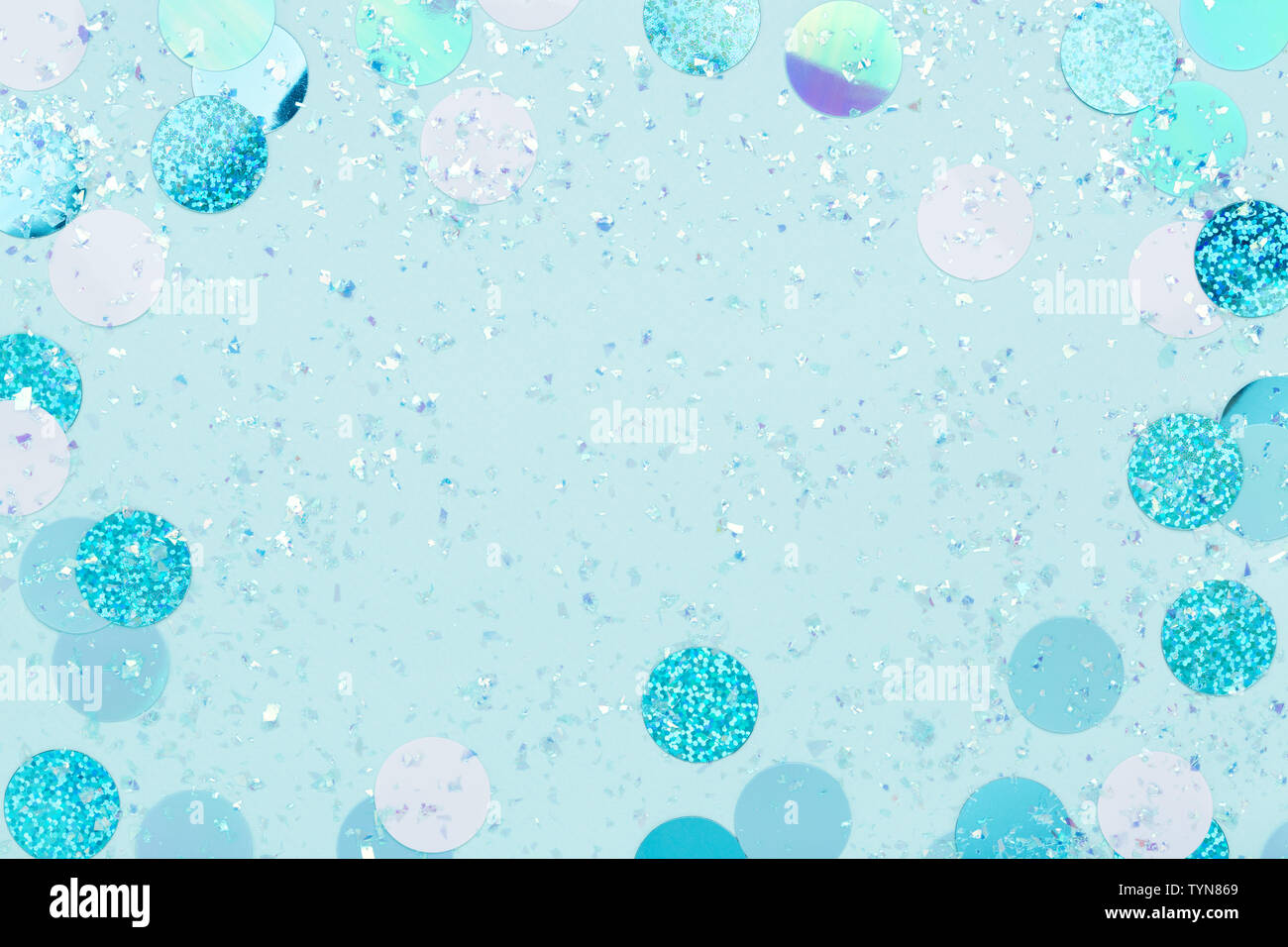 Cadre festif de confettis irisés et scintille sur fond bleu pastel. Banque D'Images