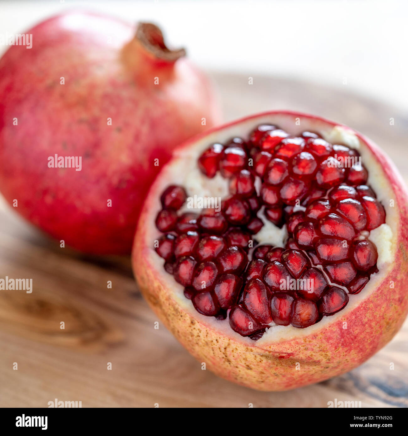 Grenadier coupés pour voir les graines close up avec une faible profondeur de foyer sur planche à découper en bois Banque D'Images